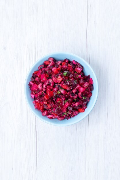 Köstlicher Rübensalat von oben in der Ferne, geschnitten mit Gemüse in der blauen Platte auf hellem Schreibtisch, Gemüse-Vitamin-Lebensmittelmahlzeit-Gesundheitssalat