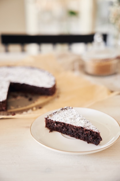 Kostenloses Foto köstlicher schokoladenkuchen mit sahne auf einem weißen tisch mit ästhetischen details präsentiert