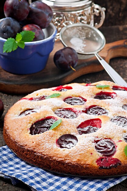 Köstlicher selbst gemachter Kuchen mit Pflaumen auf einer Holzoberfläche