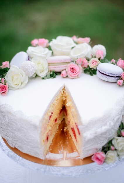 Köstlicher weißer Kuchen verziert mit rosa Makronen und Rosen