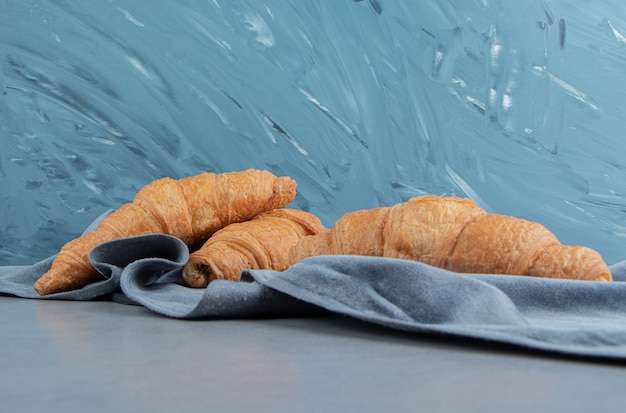 Kostenloses Foto köstliches croissant auf handtuch, auf dem blauen hintergrund. hochwertiges foto