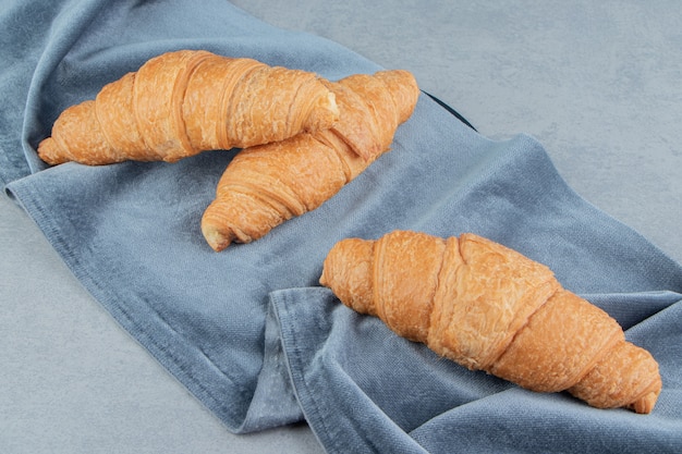 Köstliches Croissant auf Handtuch, auf dem Marmorhintergrund. Hochwertiges Foto