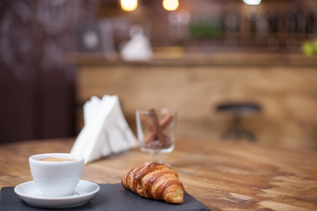 Köstliches Croissant serviert mit einer warmen Tasse Kaffee. Vintage-Café. Frisch gebacken.