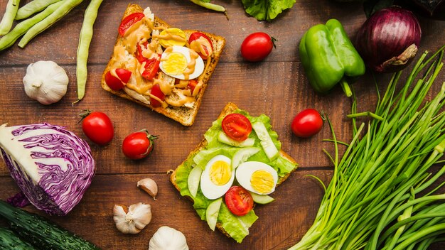 Köstliches Fleischsandwich mit unterschiedlichem gesundem Gemüse auf Holztisch