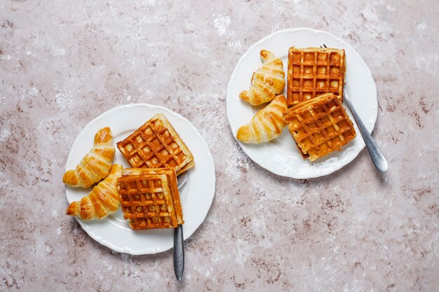 Köstliches Frühstück mit Kaffee, Orangensaft, Waffeln, Hörnchen, Stau, Nusspaste auf heller, Draufsicht