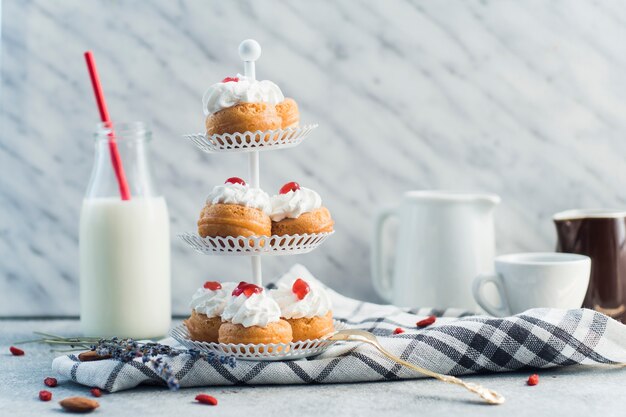 Köstliches Gebäck vereinbart auf Kuchenstand nahe Milchflaschen- und Nusslebensmittel auf Betonoberfläche