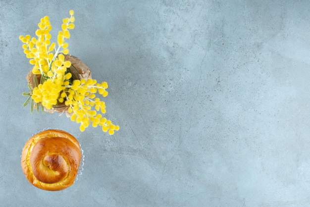 Köstliches süßes Gebäck und gelbe Blumen auf Marmor.