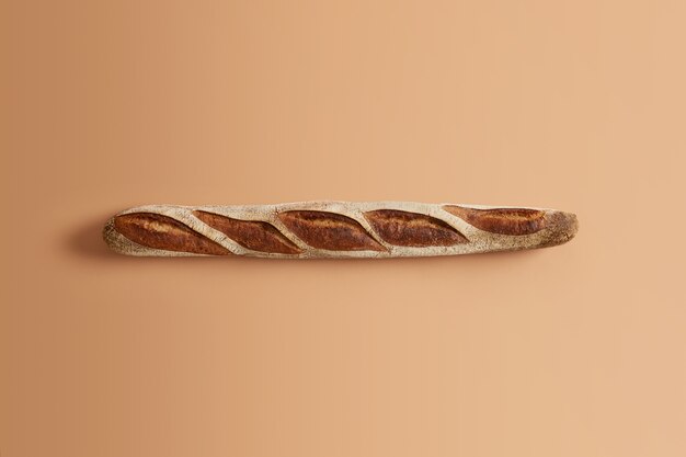 Köstliches traditionelles französisches knuspriges Baguette, das von professionell gebacken wird, bereit, verbraucht zu werden, lokalisiert auf beigem Hintergrund. Bio-Sauerteigprodukt. Hausmannskost, Bäckerei, Naturkostkonzept.