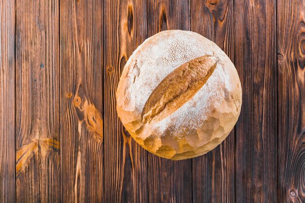 Köstliches vollständiges rundes Brot auf hölzernem Hintergrund