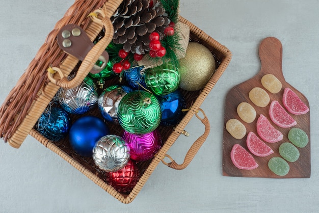 Koffer voller Weihnachtskugeln und Holzbrett mit Marmelade auf weißem Hintergrund. Hochwertiges Foto