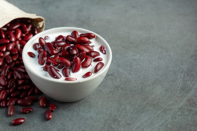 Kokosmilchdessert mit roten Bohnen in einer weißen Schüssel neben dem Sackbeutel mit roten Bohnen