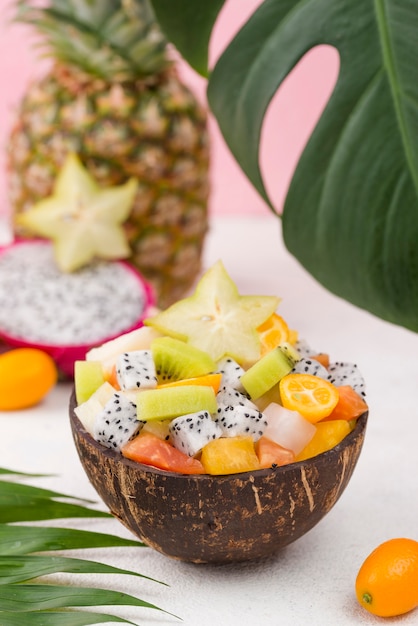 Kostenloses Foto kokosnuss gefüllt mit obstsalat und monstera-blatt