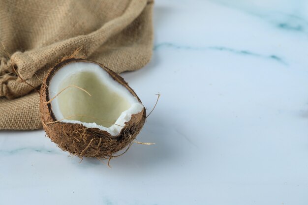 Kokosnussfrucht auf einem blauen Marmor mit Sackleinen