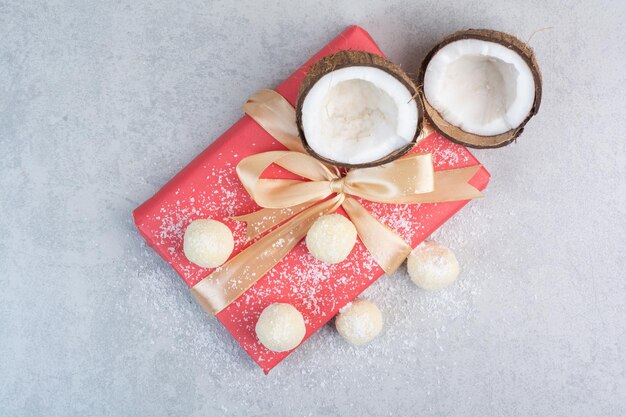 Kokosplätzchen, Kokosnüsse und Geschenkbox auf grauem Tisch. Foto in hoher Qualität