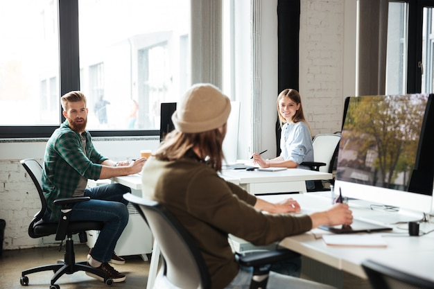 Kollegen arbeiten im Büro mit Computern. Zur Seite schauen.