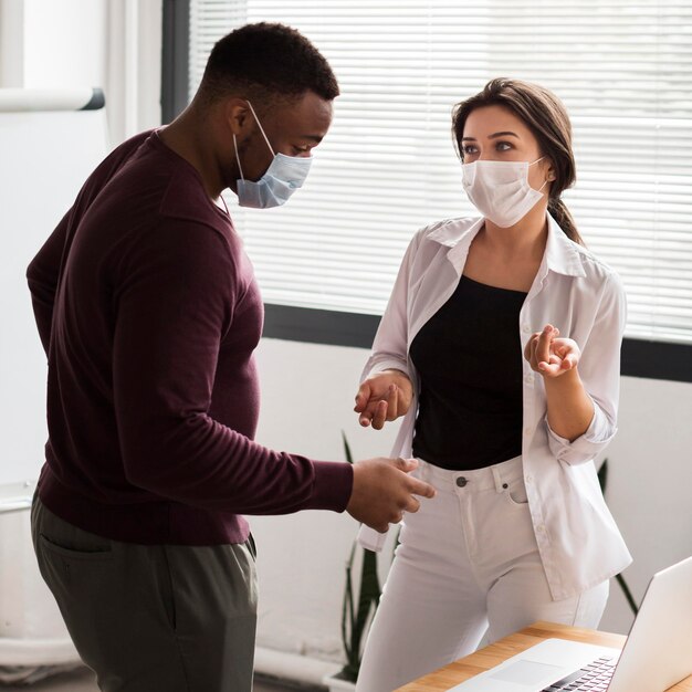 Kollegen, die während einer Pandemie mit Masken im Büro zusammenarbeiten