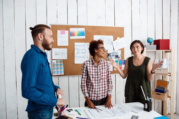 Kollegen lächeln, sprechen, Zeichnungen diskutieren, neue Ideen im Büro