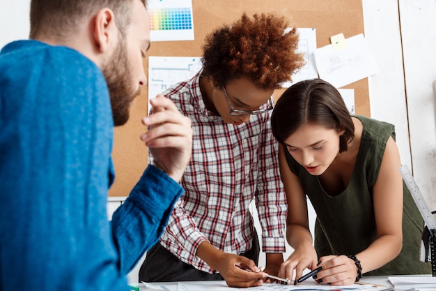 Kollegen lächeln, sprechen, Zeichnungen diskutieren, neue Ideen im Büro