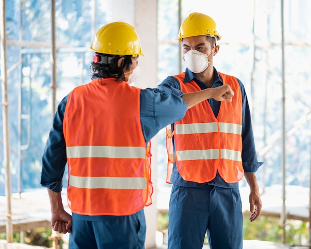 Kollegen mit Sicherheitsausrüstung, die mit Bauplänen arbeiten