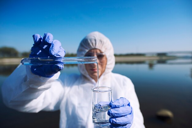 Ökologe, der mit Reagenzglas Wasser aus dem Fluss entnimmt