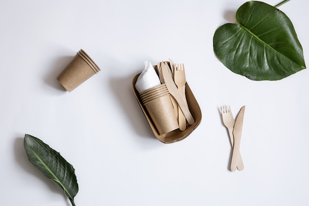Ökologisches Einweggeschirr aus Bambusholz und Papier. Tassen, Messer und Gabeln isoliert.