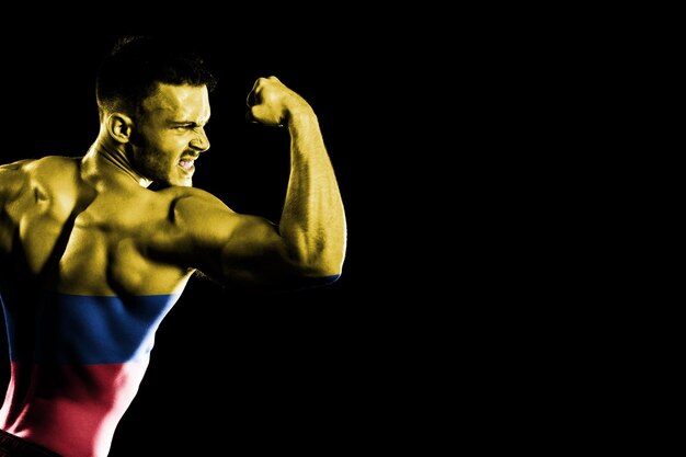 Kolumbien-Flagge auf schwarzem Hintergrund des hübschen jungen muskulösen Mannes