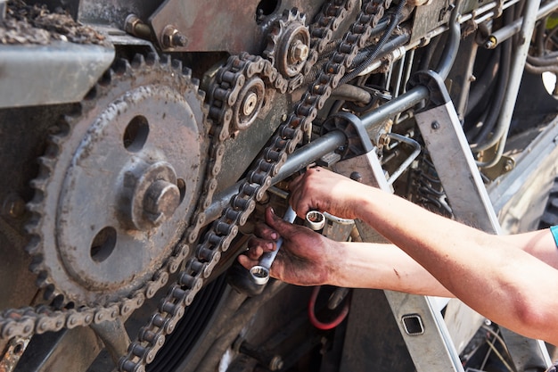 Kostenloses Foto kombinieren sie maschinenservice, mechaniker repariert motor im freien.