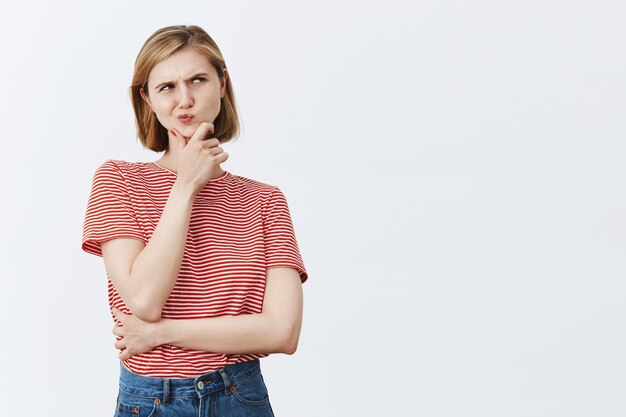 Kompliziert denkendes blondes Mädchen, das nachdenklich in der oberen rechten Ecke aussieht und die Wahl trifft