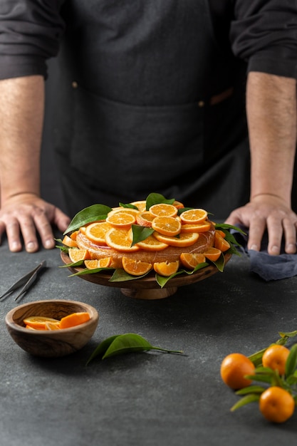 Konditor, der hinter Orangenkuchen steht