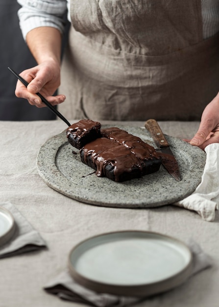 Konditor, der Schokoladenkuchen schneidet und auf Teller legt