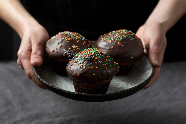 Konditor, der Teller mit Schokoladenmuffins hält