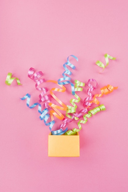 Kostenloses Foto konfetti, knallend aus geschenkbox mit rosa hintergrund heraus