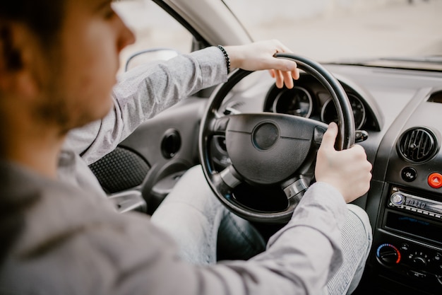 Konzentration auf die Straße. Hintere Ansicht des jungen gutaussehenden Mannes, der gerade beim Fahren eines Autos schaut