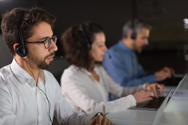 Konzentrierte bärtige Callcenter-Betreiber arbeiten