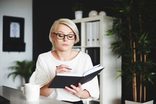 Konzentrierte Frau, die in ihrem Büro auf ein Notizbuch schreibt