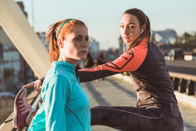 Konzentrierte Sportlerinnen Stretching vor dem Laufen