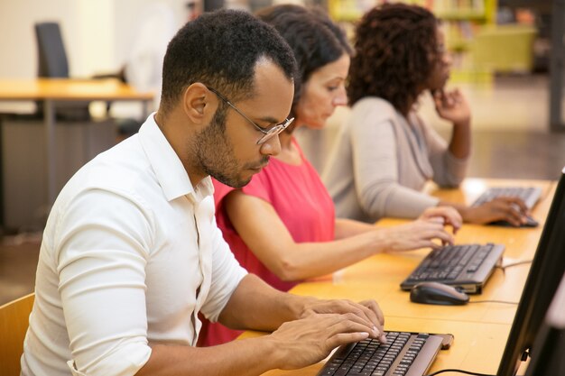 Konzentrierte Studenten, die mit Computern an der Bibliothek arbeiten