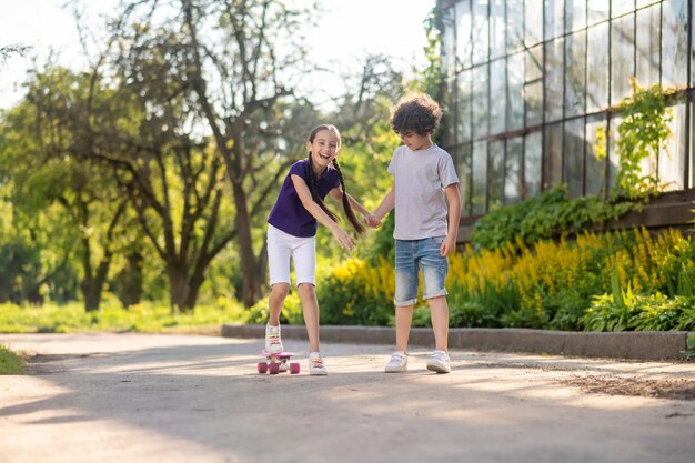 Konzentrierter Junge bringt seinem Freund das Skateboard bei