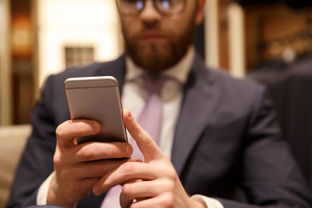 Konzentrierter junger bärtiger Geschäftsmann, der per Telefon plaudert