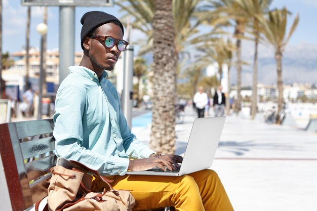 Konzentrierter junger männlicher freiberuflicher Arbeiter, der einen Notebookcomputer für Fernarbeit verwendet
