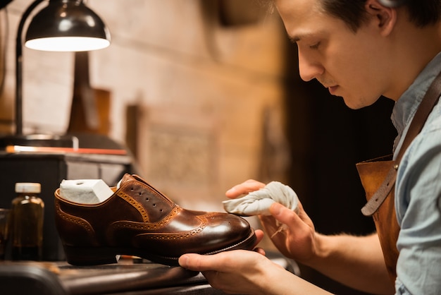 Konzentrierter Schuhmacher in der Werkstatt, der Schuhe herstellt