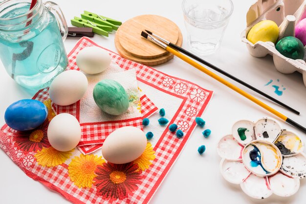 Konzept der Färbung von Eiern auf Servietten in der Nähe von Palette und Bürsten