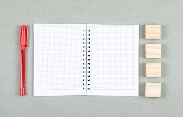 Konzept des offenen Notizbuchs und der Notiz. mit Stift, Holzklötze auf grauer Hintergrundansicht von oben. Platz für horizontales Textbild