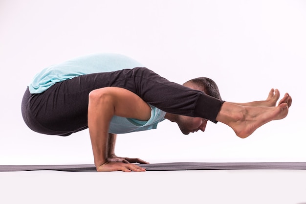 Kostenloses Foto konzept des yoga. hübscher mann, der yogaübung lokalisiert auf einem weißen hintergrund tut