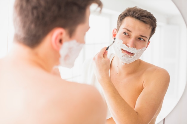 Konzept mit attraktivem jungem Mann rasieren
