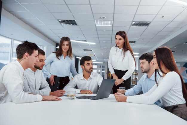 Konzeption des Erfolgs. Eine Gruppe junger Freiberufler im Büro unterhält sich und lächelt