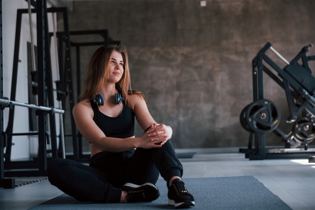 Kopfhörer am Hals. Foto der herrlichen blonden Frau im Fitnessstudio zu ihrer Wochenendzeit