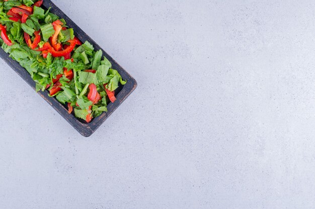 Kopfsalat und Paprikasalat aufgetürmt in einem schwarzen Tablett auf Marmorhintergrund. Foto in hoher Qualität