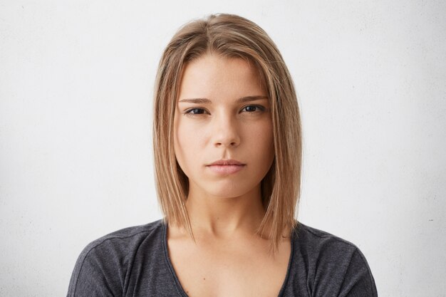 Kopfschuss einer ernsthaften jungen Frau gemischter Rassen, die ein dunkles T-Shirt trägt und ihre Augen voller Misstrauen und Enttäuschung sieht