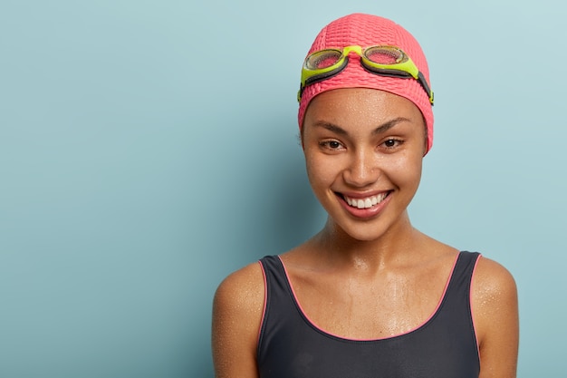 Kopfschuss einer hübschen Schwimmerin, die mit einer Schutzbrille posiert